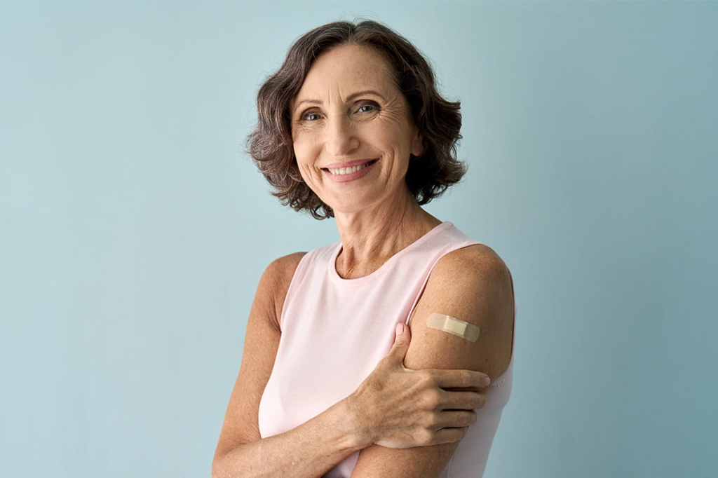 older adult woman smiling with band-aid on arm after vaccination